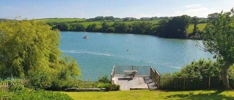 A lakeside property with a deck, a boat, and a view of the lake.
