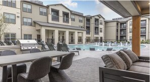 A poolside area with outdoor seating and a barbecue grill. - Landing | Amazing 2BD, Gym, Clubhouse (McKinney)
