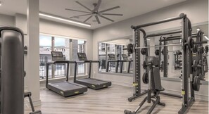 A modern gym with treadmills, weight machines, and a large mirror. - Landing | Amazing 2BD, Gym, Clubhouse (McKinney)