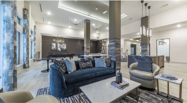 A modern living room with a sofa, armchairs, a coffee table, and a pool table. - Landing | Amazing 2BD, Gym, Clubhouse (McKinney)