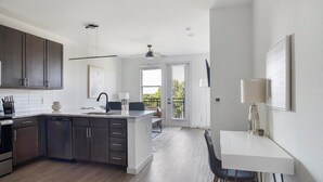 Una cucina moderna con mobili scuri, un'isola centrale e un'area pranzo con tavolo e sedie.
