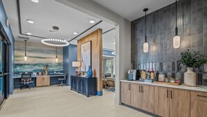 Una hall d'albergo moderna con una reception, una zona salotto e un bancone cucina con servizi.