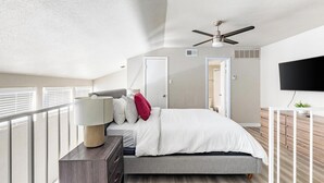A modern bedroom with a bed, bedside table, lamp, ceiling fan, and a TV on a stand. - Landing | Incredible 1BD, Pool, Gym (Fort Worth)
