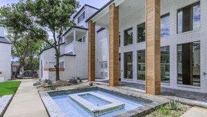 A modern building with white brick exterior, large windows, and a rectangular pool area. - Landing | Incredible 1BD, Pool, Gym (Fort Worth)