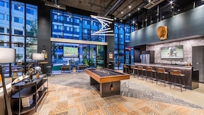Una zona de bar moderna con mesa de billar, taburetes y una pantalla de televisión.