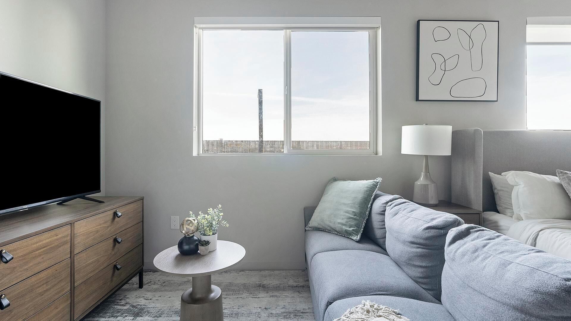 Una sala de estar moderna con una televisión de pantalla plana, un sofá, una mesa de centro y una lámpara.