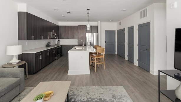 Una cocina moderna con gabinetes de madera oscura, electrodomésticos de acero inoxidable y una isla central con asientos.