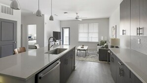 Una cocina moderna con una isla central, electrodomésticos integrados e iluminación colgante.