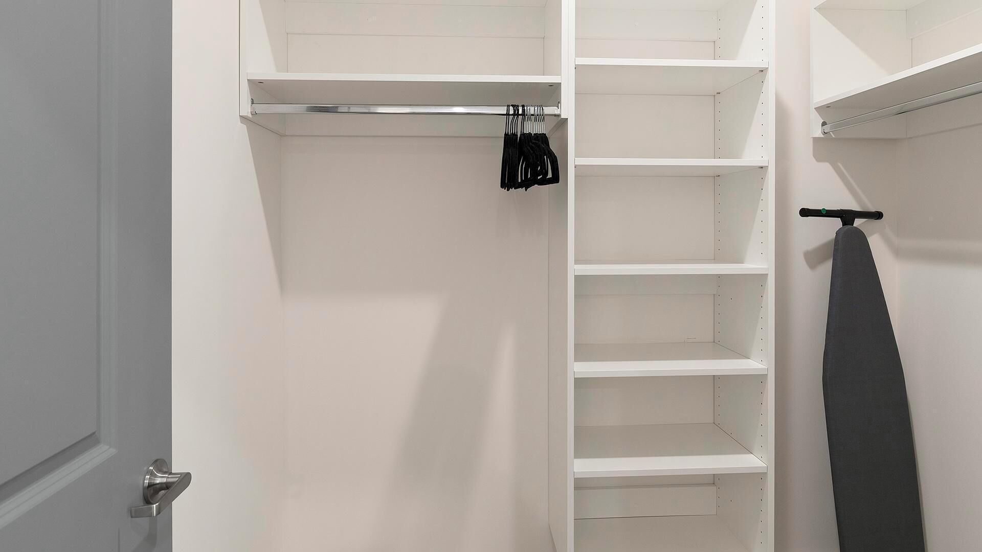 Un armario blanco con repisas abiertas y una barra para colgar.