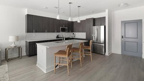 Una cocina moderna con una isla central, electrodomésticos de acero inoxidable e iluminación colgante.