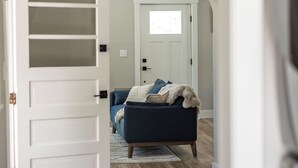 Quarto com uma cama, uma porta branca e vista para um corredor.