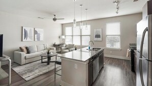 Een moderne keuken met een centraal eiland, een zithoek met een bank en een plafondventilator.