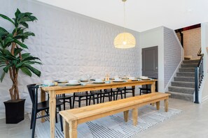 A dining area with a wooden table set for six, surrounded by black chairs, a bench, and a potted plant. - Lakefront 9 Bedroom Villa: Arcade, Themed Rooms, Lazy River (Kissimmee)