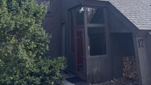 Una casa amb un teulat inclinat, trageters i una porta vermella, a més d'un petit porxo.