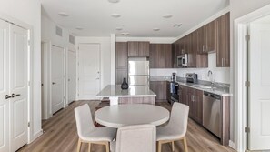 A modern kitchen with a central island, built-in appliances, and a dining area with two chairs.