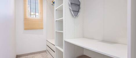 A room with a window, a white shelf unit, a patterned floor, and a bag on the floor.
