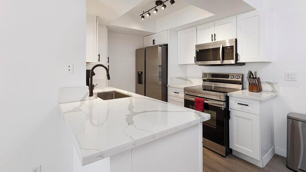 A modern kitchen with white cabinetry, stainless steel appliances, and a marble countertop. - Landing | Chic 2BD, Courtyard (Paradise)