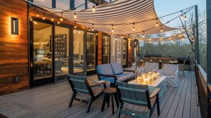 Terraza al aire libre con toldo, asientos e iluminación colgante.