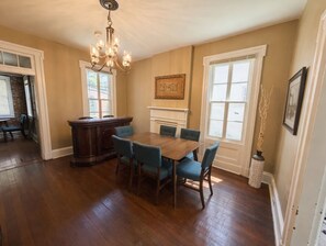 A dining room with a wooden table and chairs, a chandelier, and a fireplace.