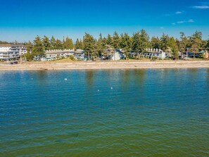 A waterfront property with multiple buildings, a sandy beach, and a calm body of water. - JL 501: Indoor pool 2 Bedroom Condo (Birch Bay)