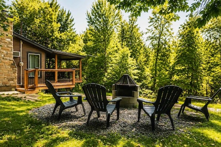 A cabin with a deck, a fire pit, and three Adirondack chairs.. Escape in the heart of Miller Zoo | Sheira Shack
