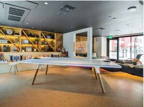 Un intérieur moderne avec une longue table, des étagères remplies de divers objets et une grande fenêtre.
