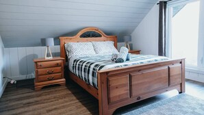 A bedroom with a wooden bed, two nightstands, a dresser, and a large window. - River & Miller Zoo | Louna-Nuage Shack (Frampton)
