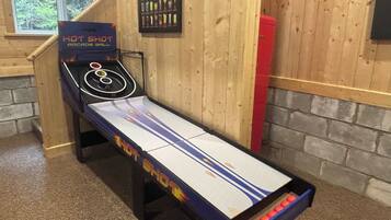 Une table de jeu d’arcade « Hot Shot », avec un sol en bois et une fenêtre en arrière-plan.