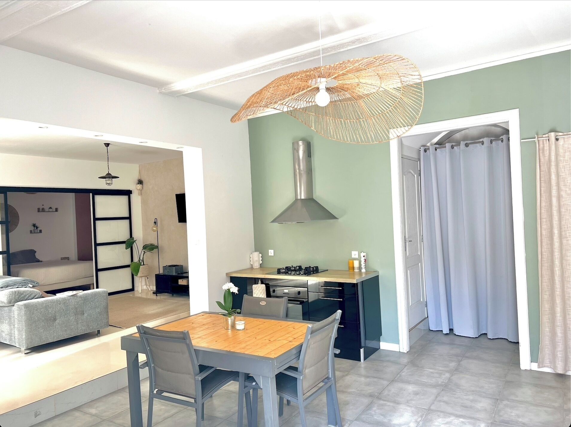 A modern kitchen with a dining area, a built-in stove, and a hanging light fixture.
