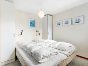 Une chambre à coucher comprenant un lit, deux lampes de chevet, un luminaire suspendu et trois tableaux accrochés au mur.