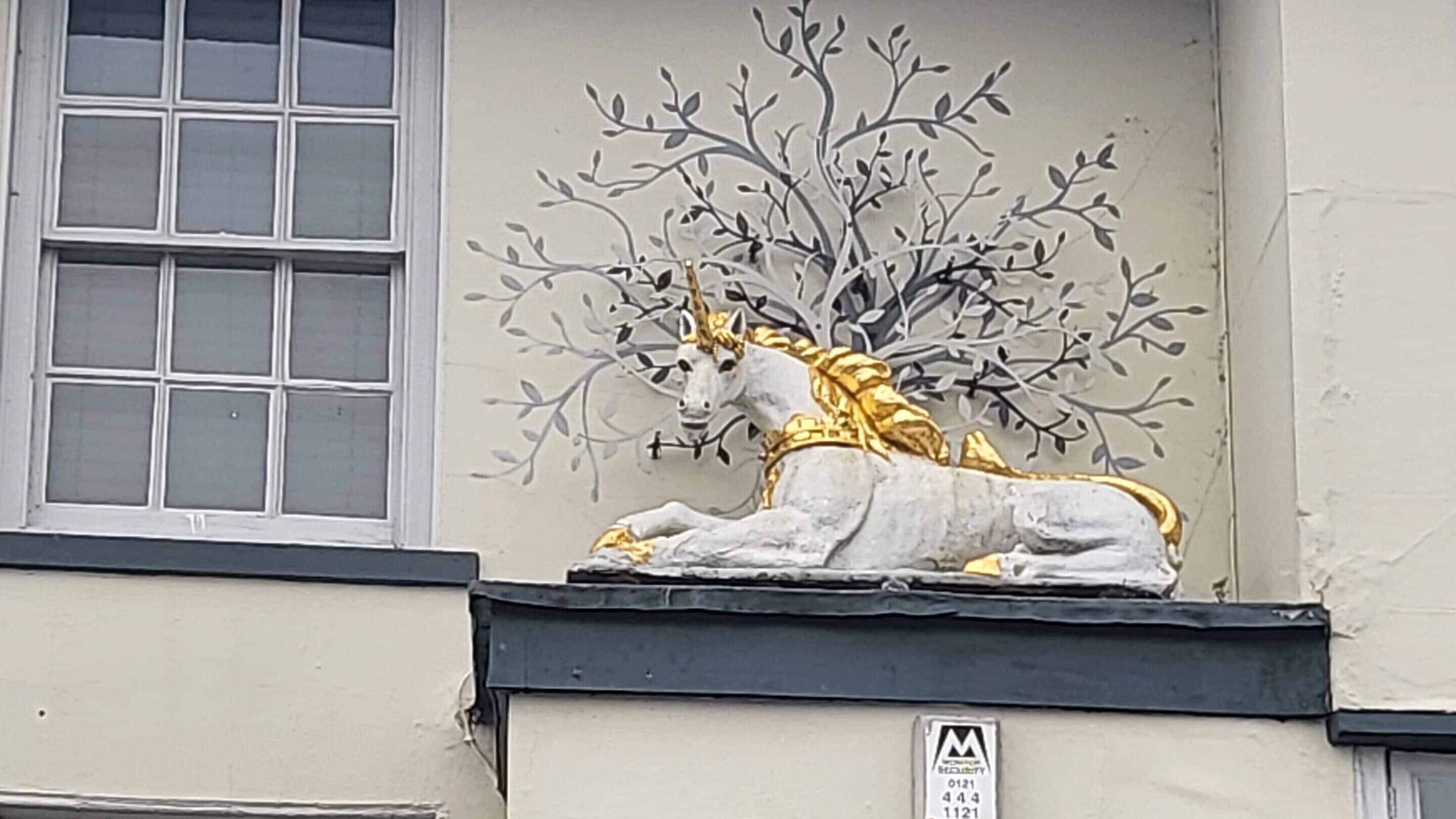 A building facade with a decorative sculpture of a horse and a tree.