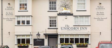 A building with 'Walled Garden En Suite Rooms' and 'Locally Sourced Food' signs, and the Unicorn Inn logo.