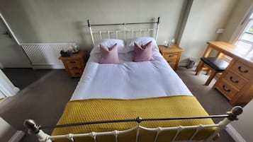 Ein Schlafzimmer mit einem Bett, Nachttischen, einer Holzkommode und einem Heizkörper.