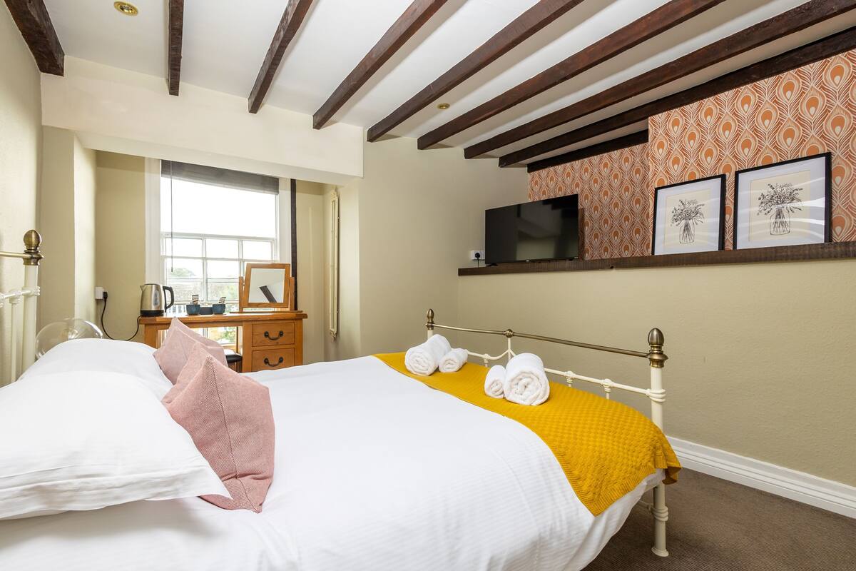 Une chambre d’hôtel avec un lit, une télévision, une fenêtre et une commode.
