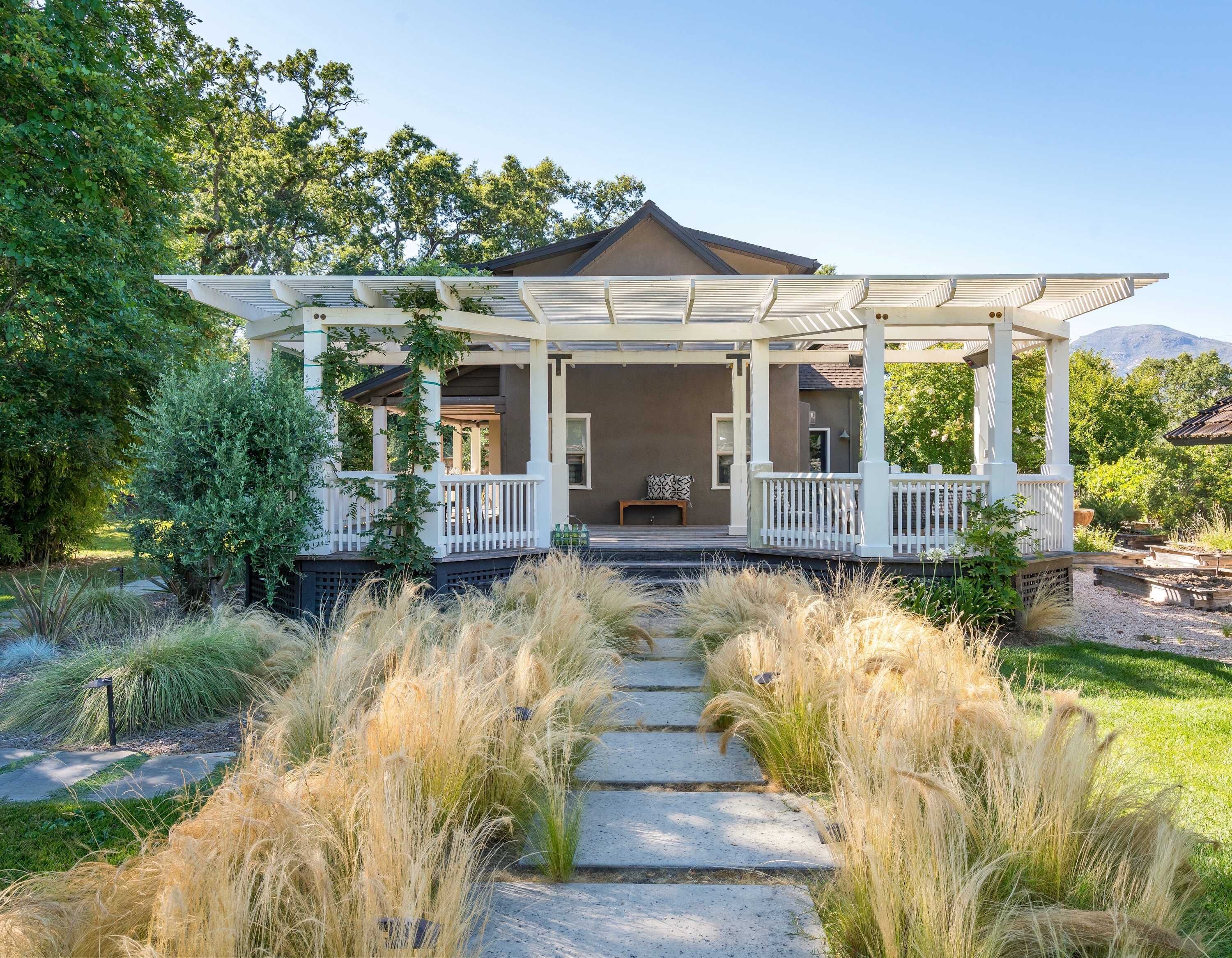 A house with a covered porch, a stone pathway, and surrounding greenery.