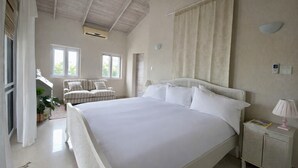 Ein Schlafzimmer mit einem großen Bett, einem Nachttisch mit Lampe, einem Fenster und einer Tür.