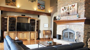 A living room with a fireplace, a television, and a stone wall. - High-End Waterfront Estate in Stratford | Relax, Unwind, Enjoy Views (Stratford)