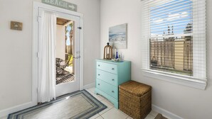 A hallway with a door labeled "BEACH," a blue dresser, a wicker basket, and a window with blinds. - Steps to Beach! Sleeps 8 + pool + garage+ beach gear + lagoon fishing + 2 patios (Panama City Beach)
