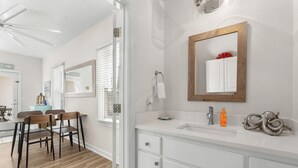 A modern bathroom with a white vanity, a large mirror, and a ceiling fan. - Steps to Beach! Sleeps 8 + pool + garage+ beach gear + lagoon fishing + 2 patios (Panama City Beach)