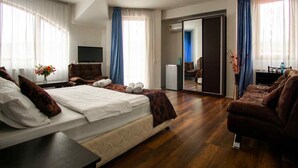 Une chambre d’hôtel équipée d’un lit, d’un canapé, d’une télévision, d’un bureau et d’un miroir.