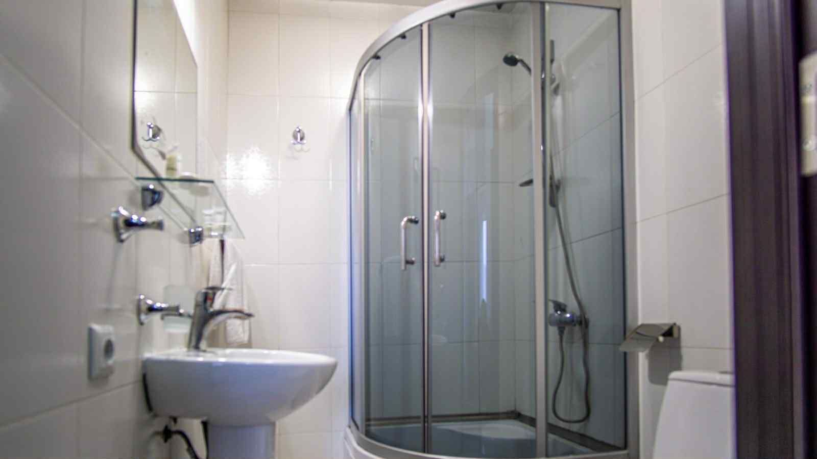 A bathroom with a glass-enclosed shower, a sink, and a mirror.