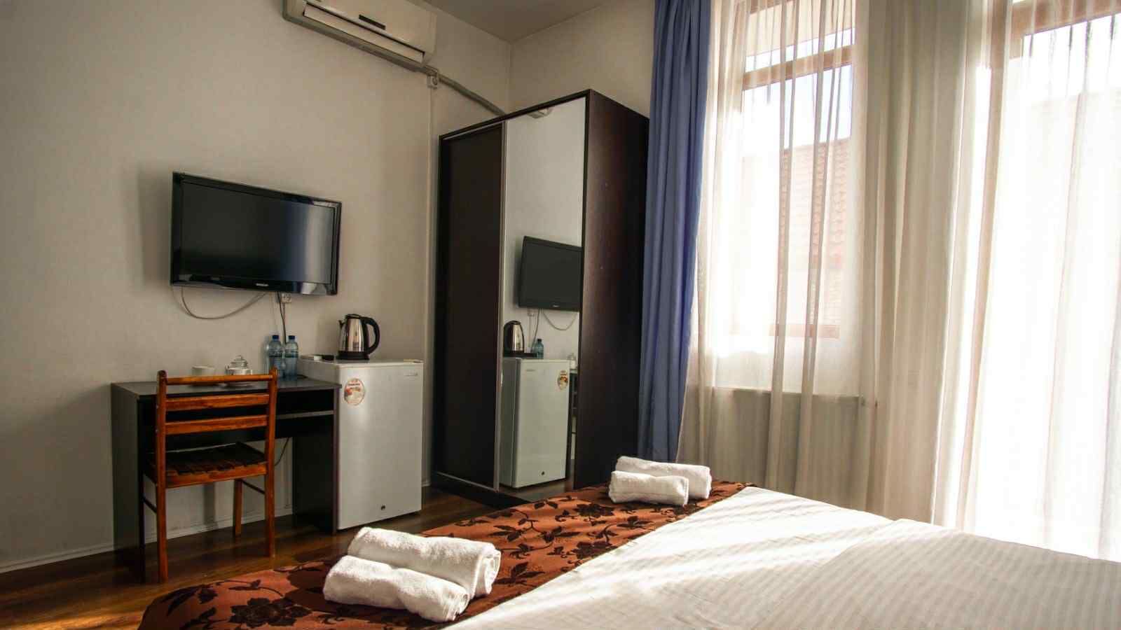 A hotel room with a bed, a desk, a television, and a wardrobe.