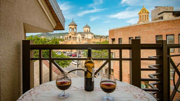 Un balcon avec une table, deux verres à vin et une bouteille de vin.