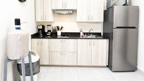 A modern kitchen with light wood cabinets, a stainless steel refrigerator, a coffee maker, and a water dispenser. - CABO DOWNTOWN STUDIOS: Cozy Queen Studios Walk to Marina #5 (Cabo San Lucas)
