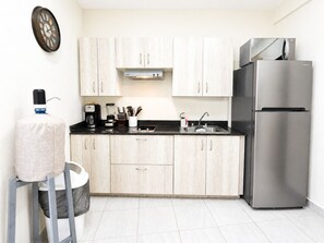 A modern kitchen with light wood cabinets, a stainless steel refrigerator, a coffee maker, and a water dispenser. - CABO DOWNTOWN STUDIOS: Cozy Queen Studios Walk to Marina #5 (Cabo San Lucas)