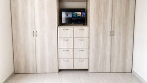 A room with a built-in TV shelf, a wardrobe with multiple drawers, and a tiled floor. - CABO DOWNTOWN STUDIOS: Cozy Queen Studios Walk to Marina #5 (Cabo San Lucas)
