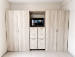 A room with a built-in TV shelf, a wardrobe with multiple drawers, and a tiled floor. - CABO DOWNTOWN STUDIOS: Cozy Queen Studios Walk to Marina #5 (Cabo San Lucas)