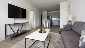 A modern living room with a flat-screen TV, a coffee table, and a sofa. - Landing | Modern 1BD, Clubhouse, Gym (Charlotte)