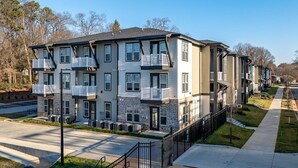 A multi-story apartment building with balconies, a parking lot, and a well-maintained lawn. - Landing | Modern 1BD, Clubhouse, Gym (Charlotte)
