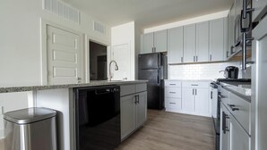 A modern kitchen with white cabinets, a stainless steel dishwasher, a black refrigerator, and a microwave. - Landing | Modern 1BD, Clubhouse, Gym (Charlotte)